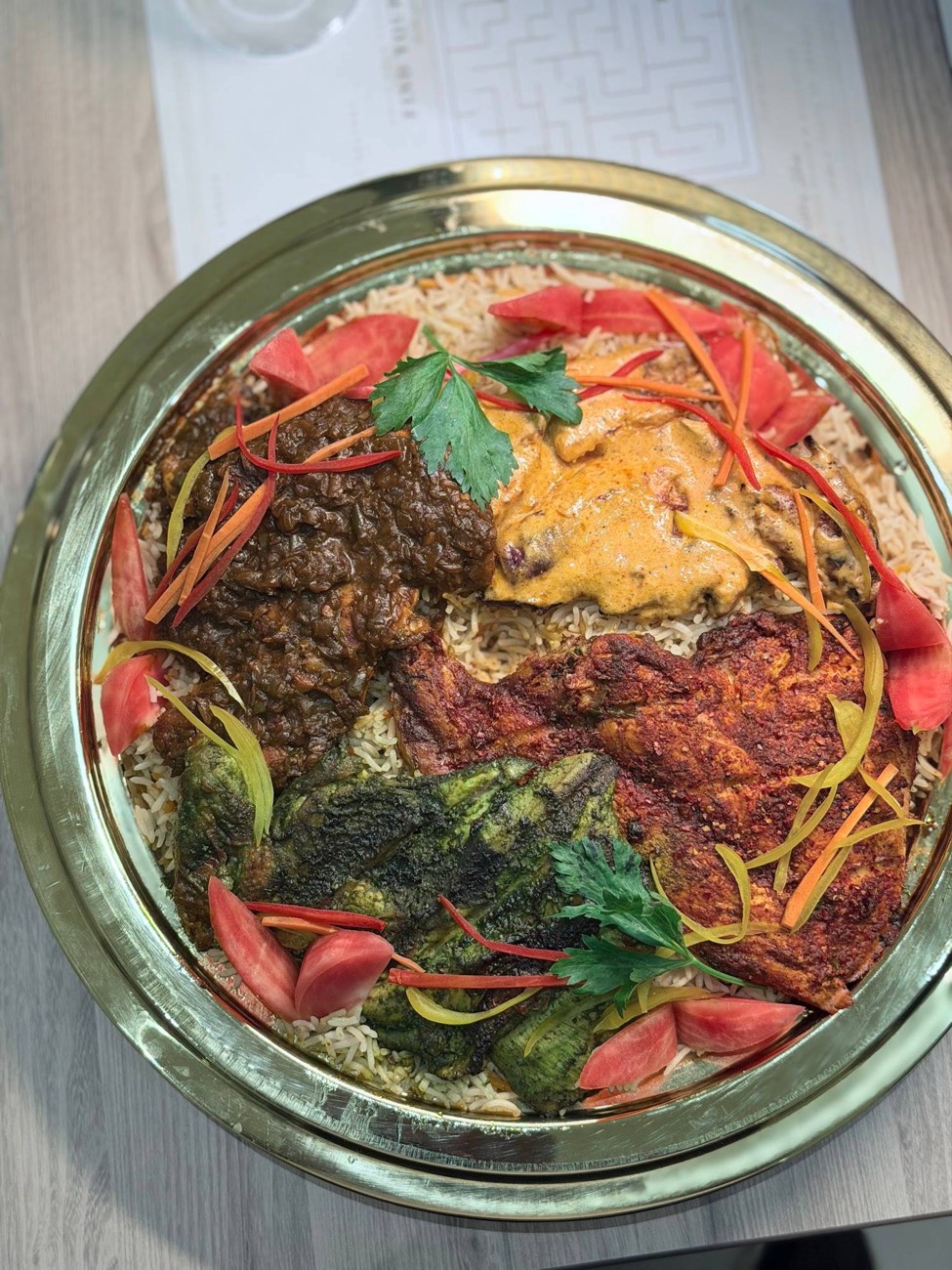 A Zahab tray of Mandhi rice topped with four charcoal grills
